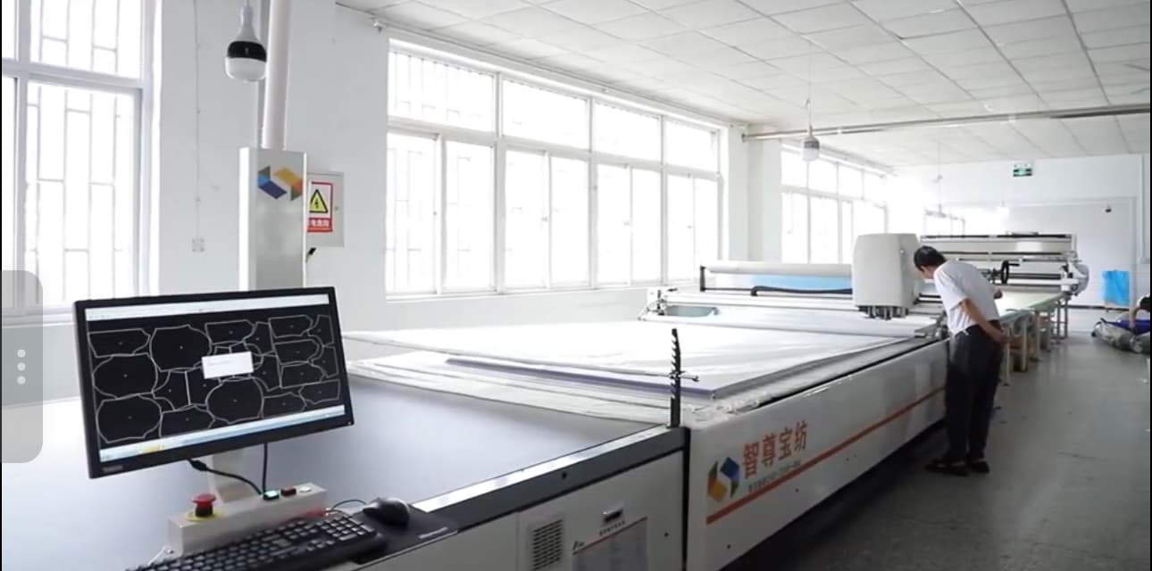 Computer-controlled fabric cutting equipment in the AIHEHUA cutting room
