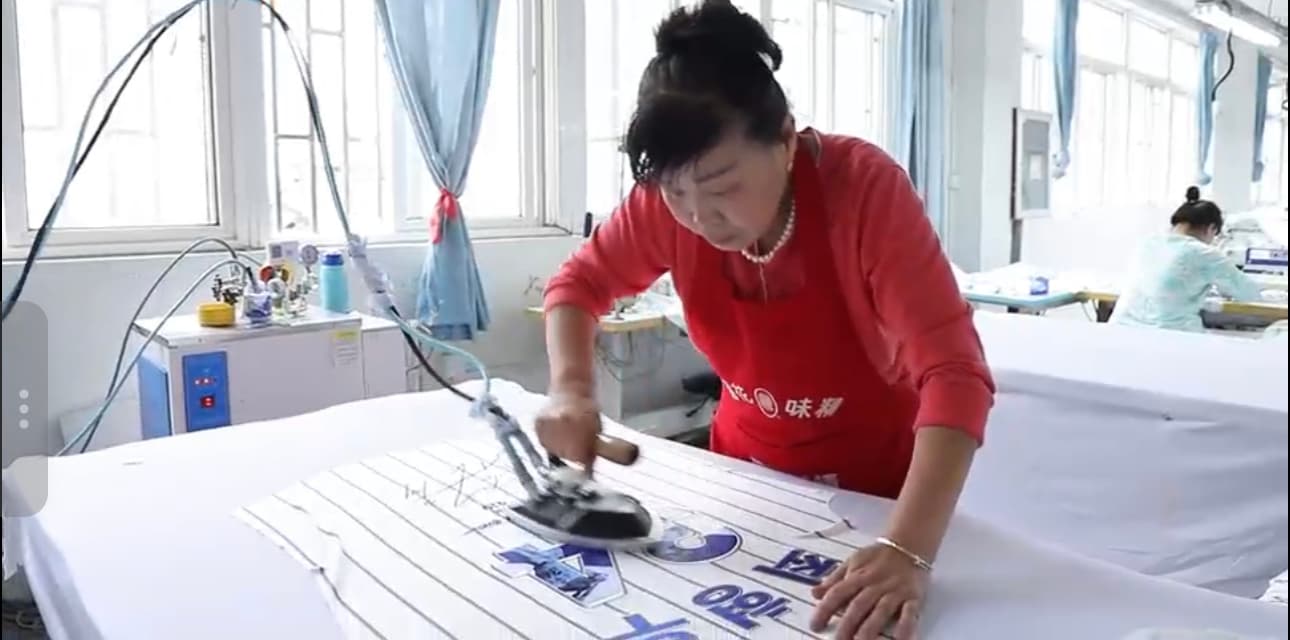 Operator applying a garment decoration process using heat press equipment