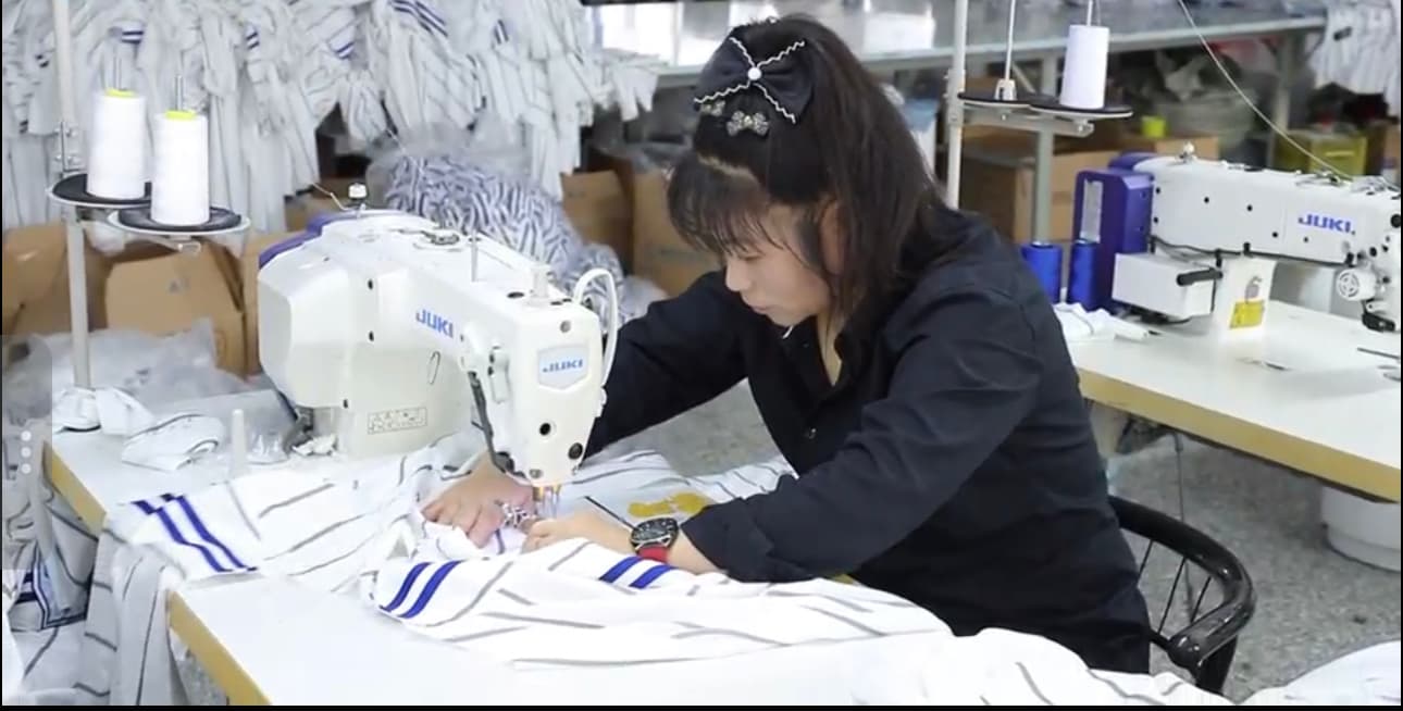 Sewing operator assembling a custom jersey at an industrial sewing station