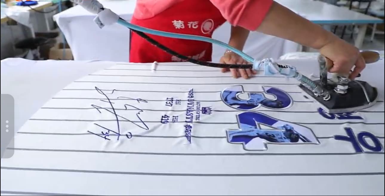 Technician heat-pressing numbers and lettering onto a jersey panel