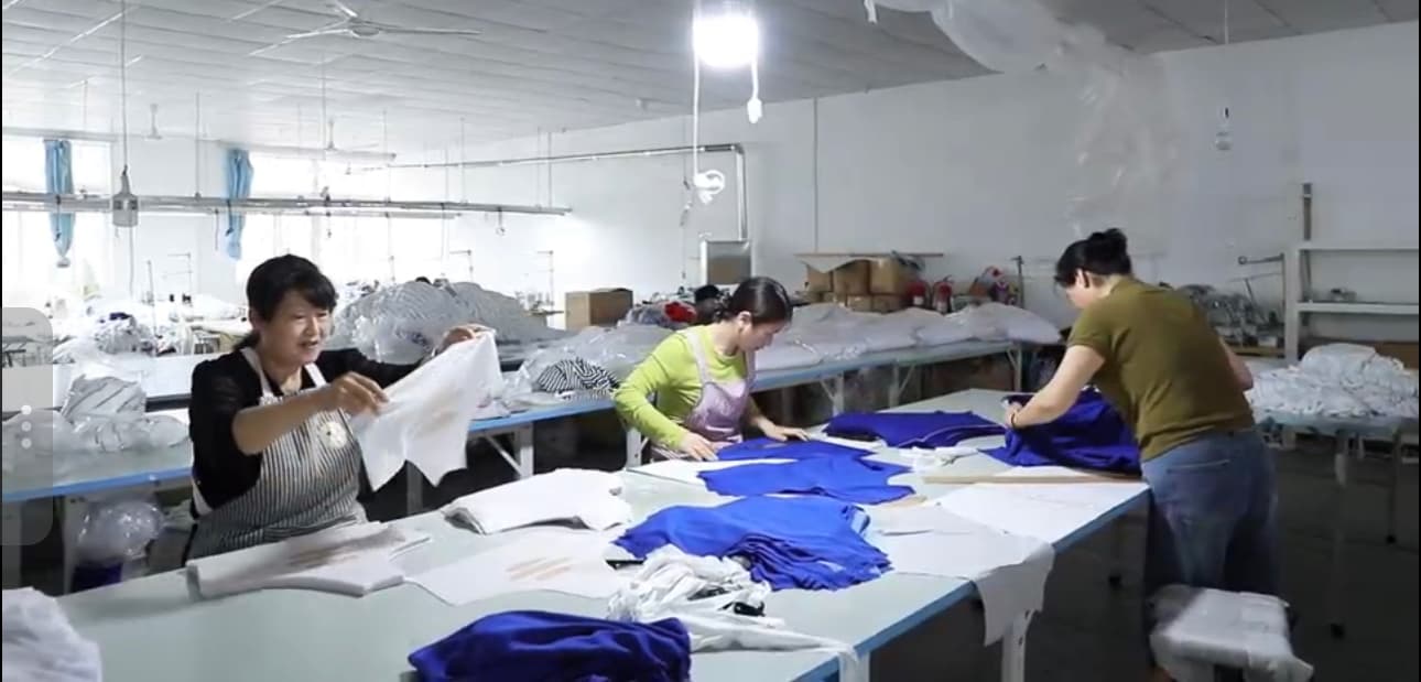 Team members sorting finished garments at the packing table